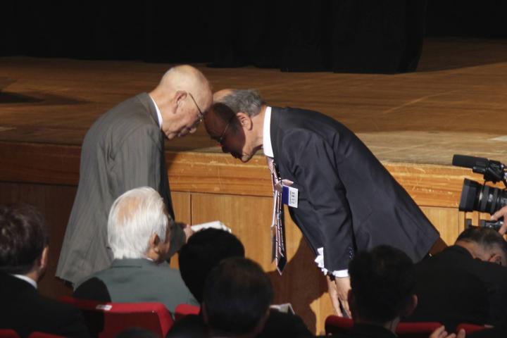 大会委員長L石丸保志(右)から大会参加長寿賞を受章するL沼田正男。